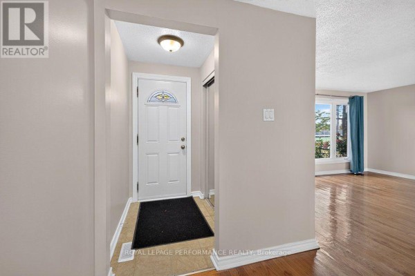 View from the entryway into the living room with hardwood floors and a window. - 2258 Russell Road, Ottawa