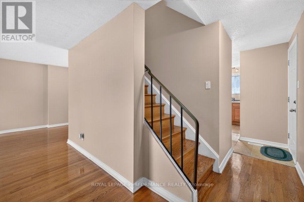 Interior view showing the hallway, staircase with black railings, and hardwood floors. - 2258 Russell Road, Ottawa
