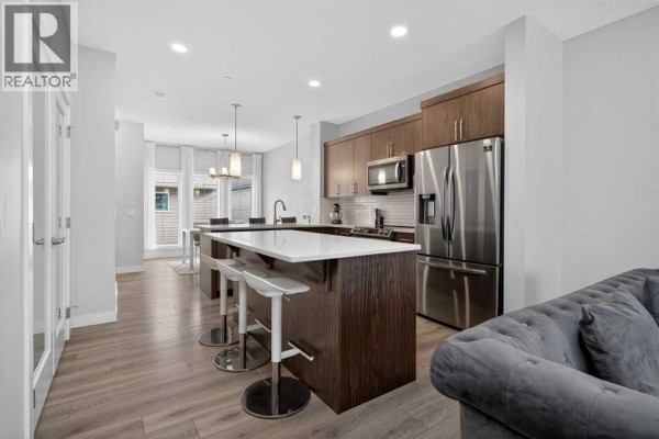 A kitchen with a large island, dark wood cabinets, and a stainless steel refrigerator and oven. - 226 148 Avenue Nw, Calgary