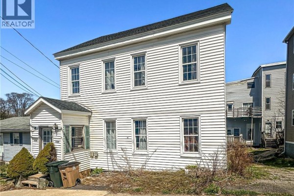 Side view of a two-story white clapboard house with two green trash bins by the porch. - 226-228 Watson Street, Saint John