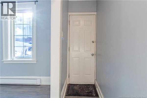 Interior view of a small hallway with a white door and a window with white trim. - 226-228 Watson Street, Saint John