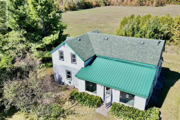 Close-up aerial view of the white house with a green metal roof and white trim. - 226 Bartley Drive, Northern Bruce Peninsula