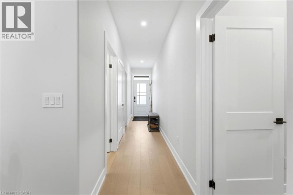 Interior view of a bright, white hallway with light wood flooring and several closed doors. - 226 Lafayette Street E, Jarvis