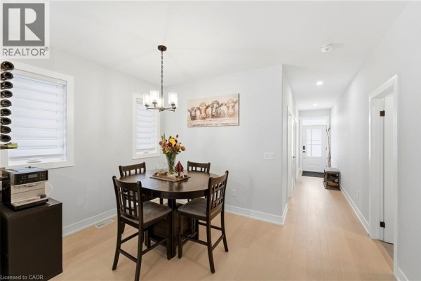 Dining area with a round table, four chairs, and a chandelier, adjacent to a hallway and entryway. - 226 Lafayette Street E, Jarvis