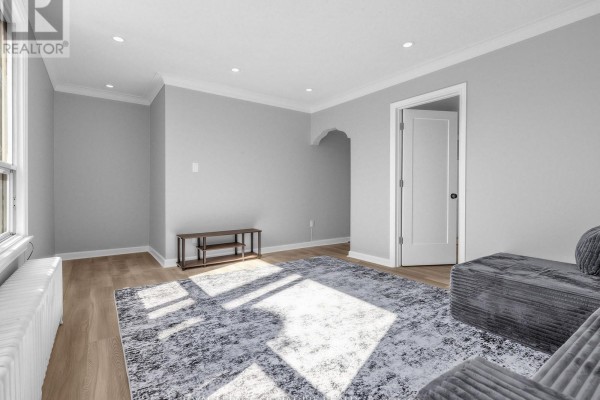 Living room with sectional sofa, patterned rug, and archway leading to another room. - 2260 Eglinton Avenue W, Toronto