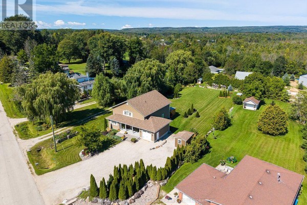 Aerial view of the property showing the house, lawn, trees, and surrounding landscape. - 226083 Centreville Road, Meaford
