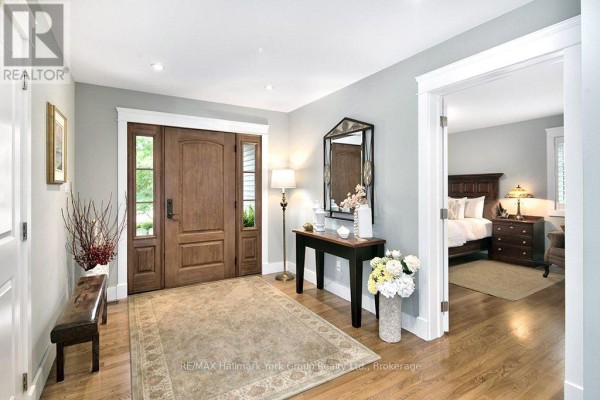 Interior entryway with a wooden front door, rug, bench, console table, and doorway to a bedroom. - 226083 Centreville Road, Meaford