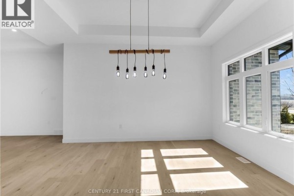 Dining area with white walls, light wood floors, a coffered ceiling, and a contemporary chandelier. - 22664 Queens Line, West Elgin