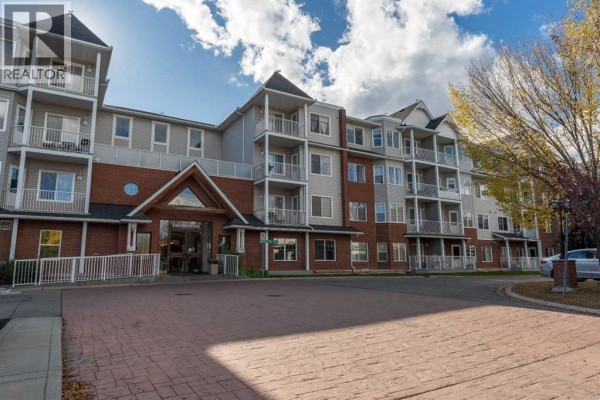 Front view of a multi-story apartment building with balconies, brick and siding exterior, and paved entrance. - 227, 8 Prestwick Pond Terrace Se, Calgary