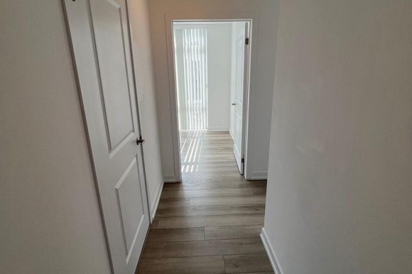 Hallway with two white doors and view into a bright room with vertical blinds. - 227 - 460 Dundas Street E, Hamilton