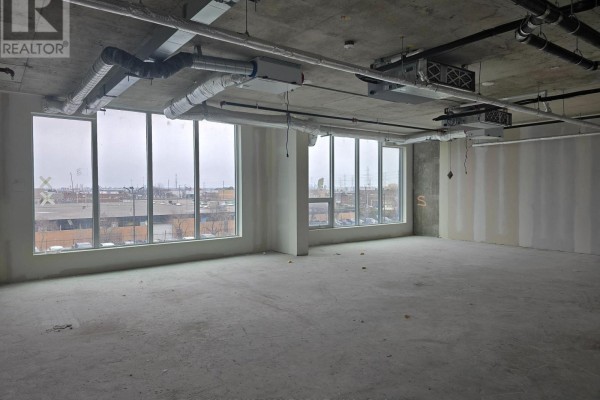 Empty commercial space with concrete floor, unfinished drywall walls, and large windows with an urban view. - 227 - 600 Dixon Road, Toronto