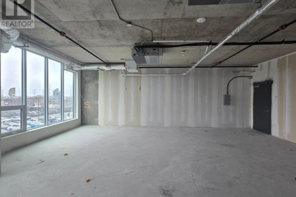 Corner view of an unfinished commercial space with concrete floor, exposed ducts, drywall, and a distant city view. - 227 - 600 Dixon Road, Toronto