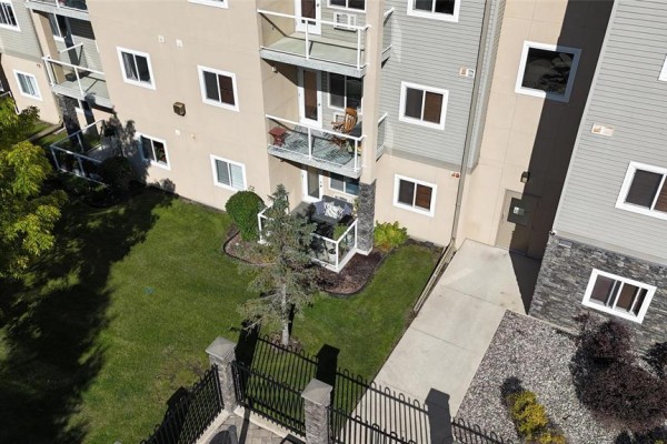 Close-up of apartment balconies and ground-level patio with grass and landscaping. - 227 230 Fairhaven Road, Winnipeg