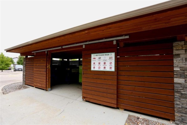 Exterior view of a wooden recycling shelter with stone pillars and signage. - 227 230 Fairhaven Road, Winnipeg