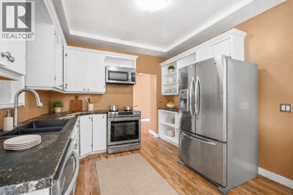 Entrance hall with a glass-paned door, beige walls, and wood-look laminate flooring. - 227 4 Street Sw, Medicine Hat