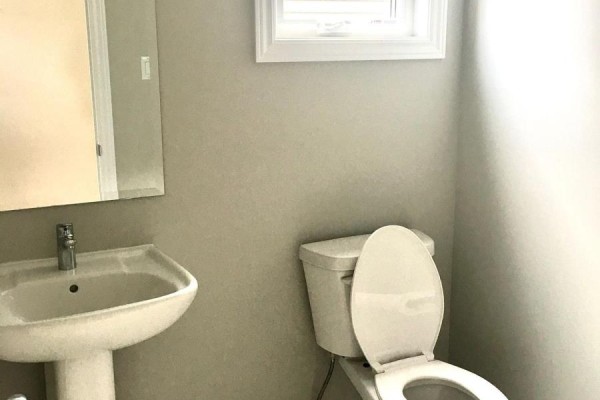 A small powder room with a pedestal sink, toilet, and a mirror on the wall. - 227 Bandelier Way, Ottawa