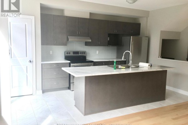 Modern kitchen with dark grey cabinetry, a marble island, stainless steel appliances, and light tile flooring. - 227 Bandelier Way, Ottawa