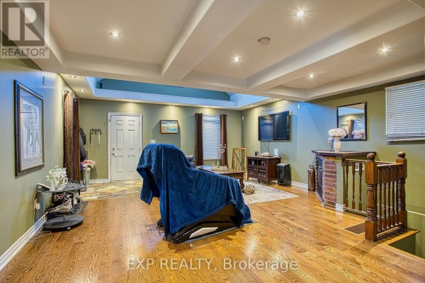 Living room with wood floors, vaulted ceiling, fireplace, and staircase, viewed from the side. - 227 Beach Road, Hamilton