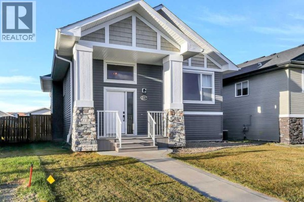 Gray house exterior with white trim, gray siding, and stone column accents. - 227 Livingston Close, Red Deer