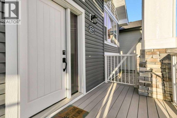 View of the gray front door and porch with white railings and siding. - 227 Livingston Close, Red Deer