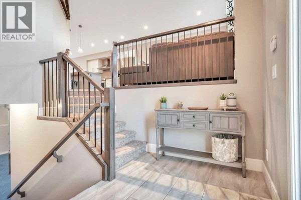 Interior view of a foyer with a gray console table, staircase, and tiled floor. - 227 Livingston Close, Red Deer
