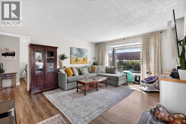 Living room with a sectional sofa, large cabinet, and floor-to-ceiling window with a view of the backyard. - 227 Lynnwood Drive Se, Calgary