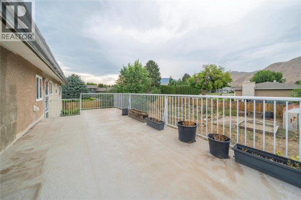 Kitchen with white cabinets, black appliances, and a washer and dryer. - 2270 Greenfield Avenue, Kamloops