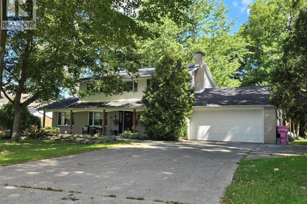 Exterior view of a light-colored two-story home with a brick base and gabled roof. - 22707 Creek Road, Chatham