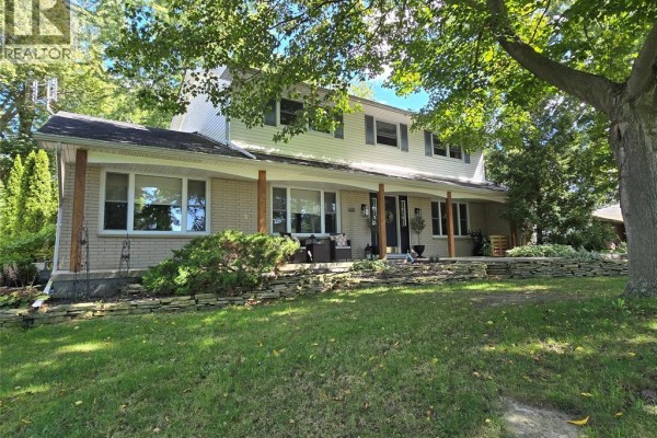 View of the house facade showcasing beige brick, white siding, and a large front porch. - 22707 Creek Road, Chatham