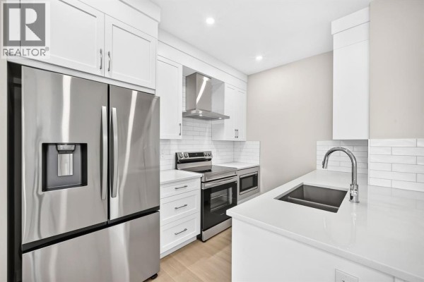 Close-up of a white kitchen island with a sink and stainless steel faucet. - 2274 Bayview Drive Sw, Airdrie