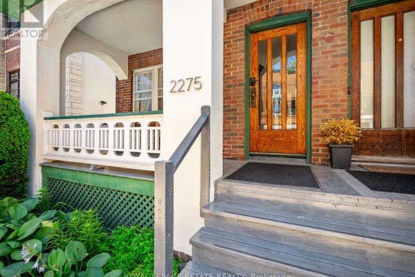 Close-up of the wood front doors and steps leading to the multi-family residence. - 2275 Queen Street E, Toronto