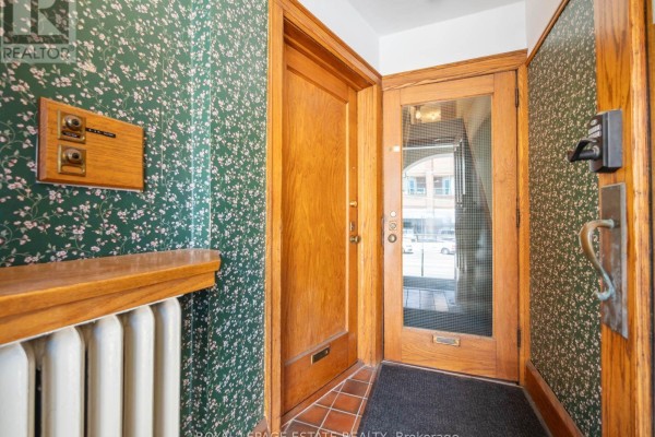 Interior entryway with patterned wallpaper, wood doors, and a radiator. - 2275 Queen Street E, Toronto