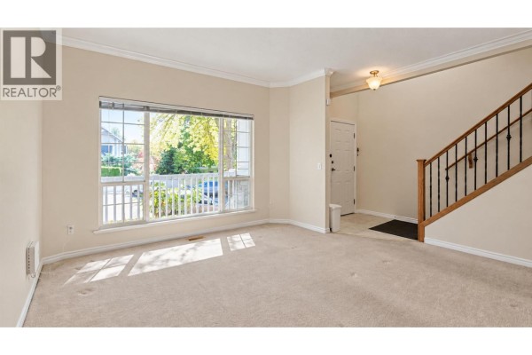 Living room with tan carpet, a large bay window, and stairs leading to the second floor. - 22789 116 Avenue, Maple Ridge