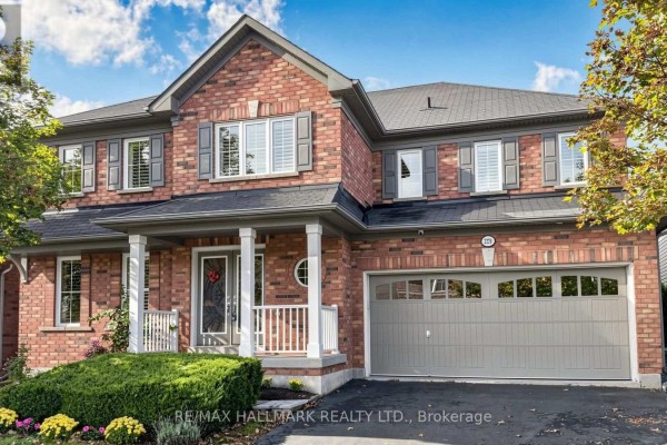 Front exterior of a two-story red brick house with grey shutters and a two-car garage. - 2279 Hackett Place, Oshawa
