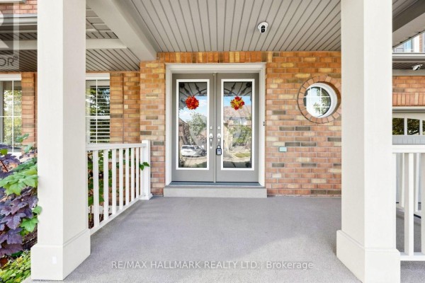 Covered front porch with white columns, railings, and double glass front doors. - 2279 Hackett Place, Oshawa
