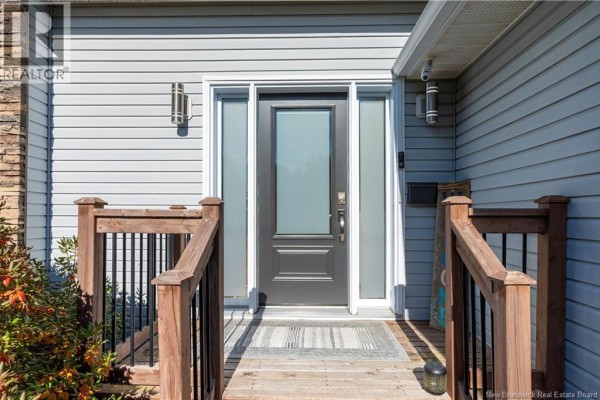 Front entrance with a grey door, glass sidelights, and wooden deck with railings. - 228 Herve Street, Dieppe