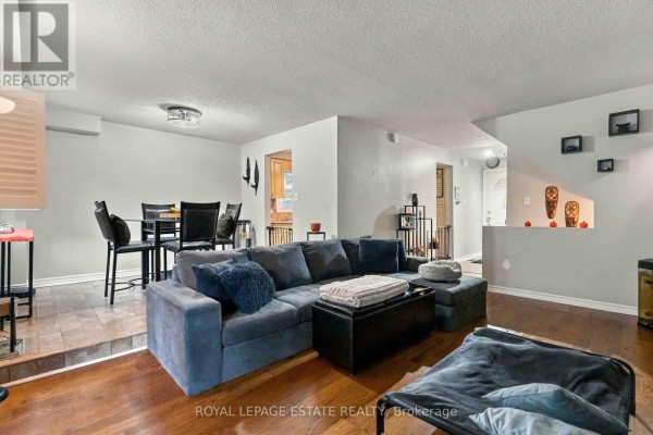 Living room with a sectional sofa, wooden floors, and dining area. - 228 Rands Road, Ajax