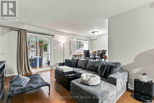 Living room with a large sofa, sliding glass doors to a deck, and dining area. - 228 Rands Road, Ajax