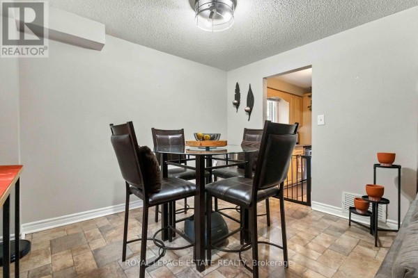 Round glass-top dining table with four leather chairs and view into the kitchen. - 228 Rands Road, Ajax