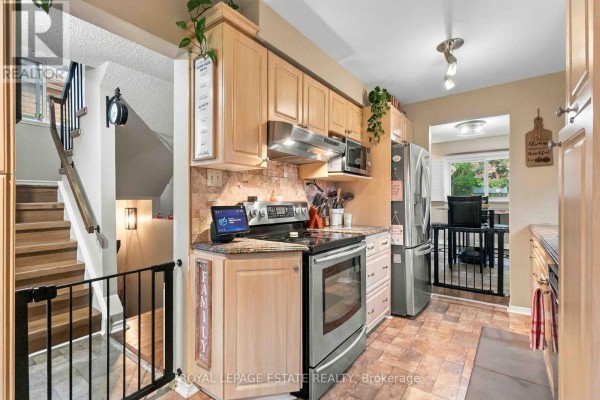 Kitchen with light wood cabinets, stainless steel appliances, and a staircase nearby. - 228 Rands Road, Ajax
