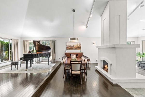 Living and dining area featuring a grand piano on a raised platform and a long dining table. - 2289 131a Street, Surrey