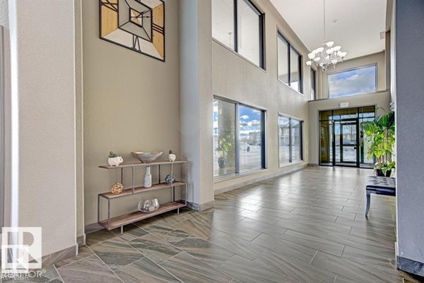 Spacious apartment building lobby with tile floors, high ceilings, large windows, and modern chandelier. - #229 1520 Hammond Gate Nw, Edmonton