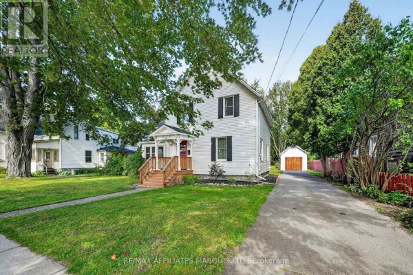 Exterior view of a white house with a long driveway leading to a garage. - 229 4th Street E, Cornwall