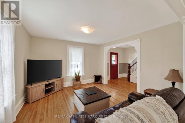Living room with hardwood floors, a large TV, and a leather recliner. - 229 4th Street E, Cornwall