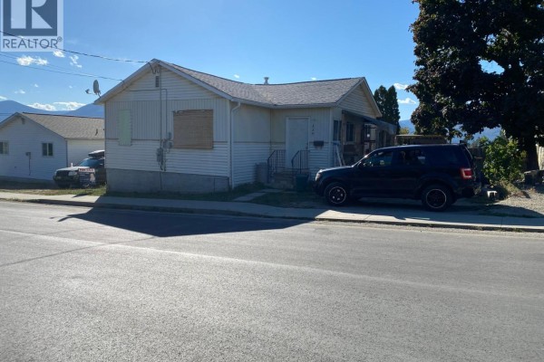 Front exterior of a white sided house with covered porch and parked vehicles. - 229 9th  S Avenue, Creston