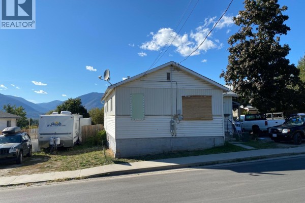 Rear exterior of a white sided house with RV and vehicles parked on property. - 229 9th  S Avenue, Creston