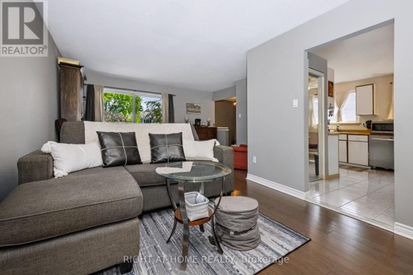 Living room with a grey sectional sofa, dark wood floors, and a sliding glass door to a balcony. - 229 Britannia Avenue, Bradford West Gwillimbury
