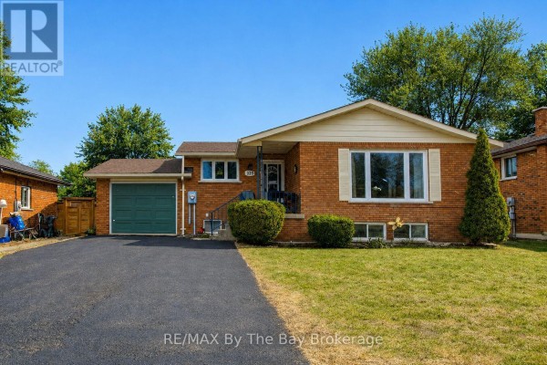 Front view of a brick bungalow with a green garage door and a clear blue sky. - 229 Datas Drive E, Clearview