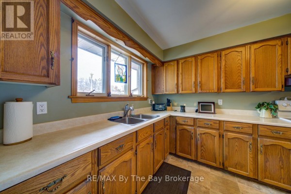 Kitchen with light wood cabinets, beige countertops, double sink, and a window. - 229 Datas Drive E, Clearview