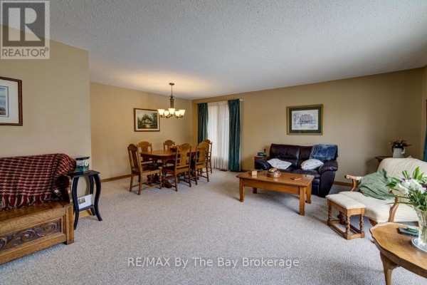 Living and dining room with beige carpet, wooden dining set, and leather sofa. - 229 Datas Drive E, Clearview